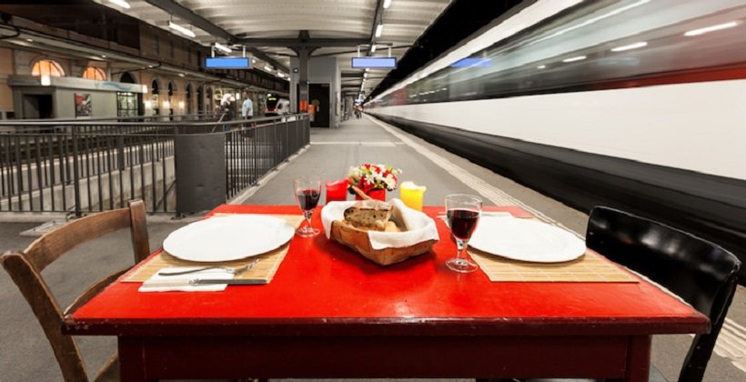 laid table for two persons on the sidewalk of a train station, outdoors
